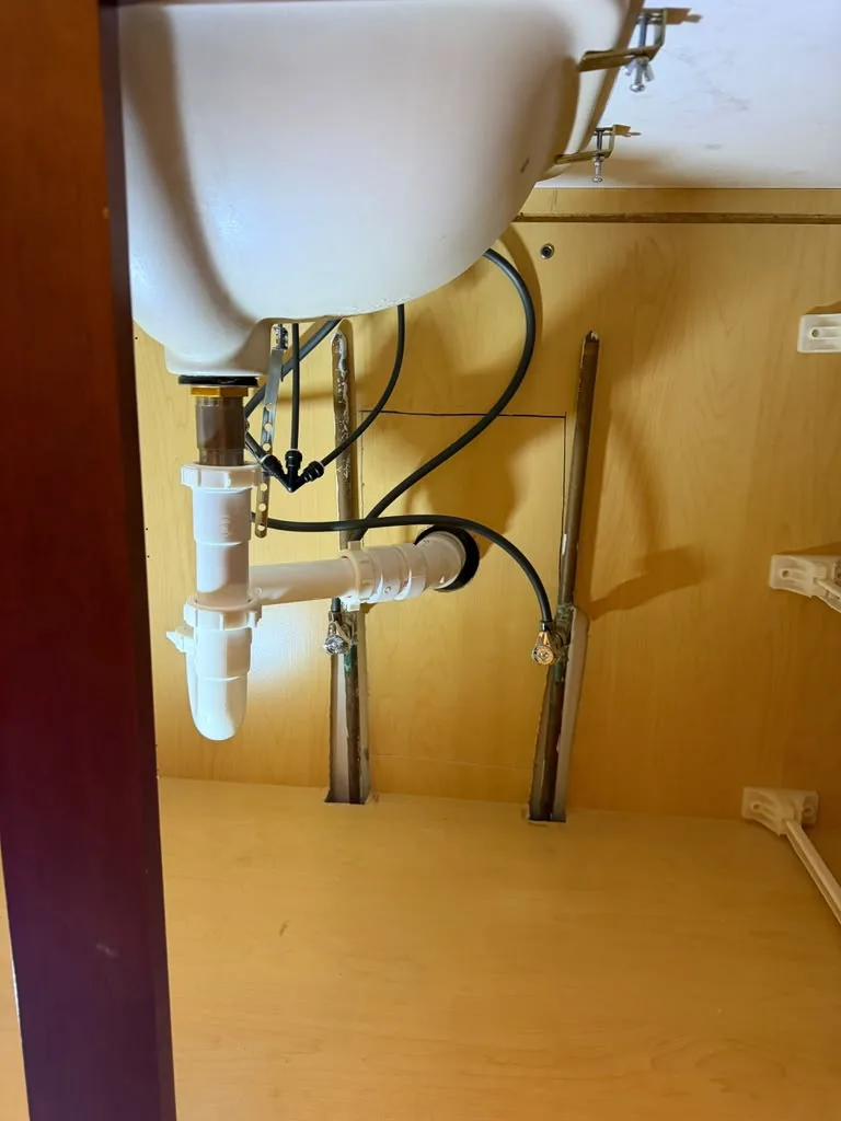 Sink drain pipe assembly installed beneath a bathroom sink in a new cabinet
