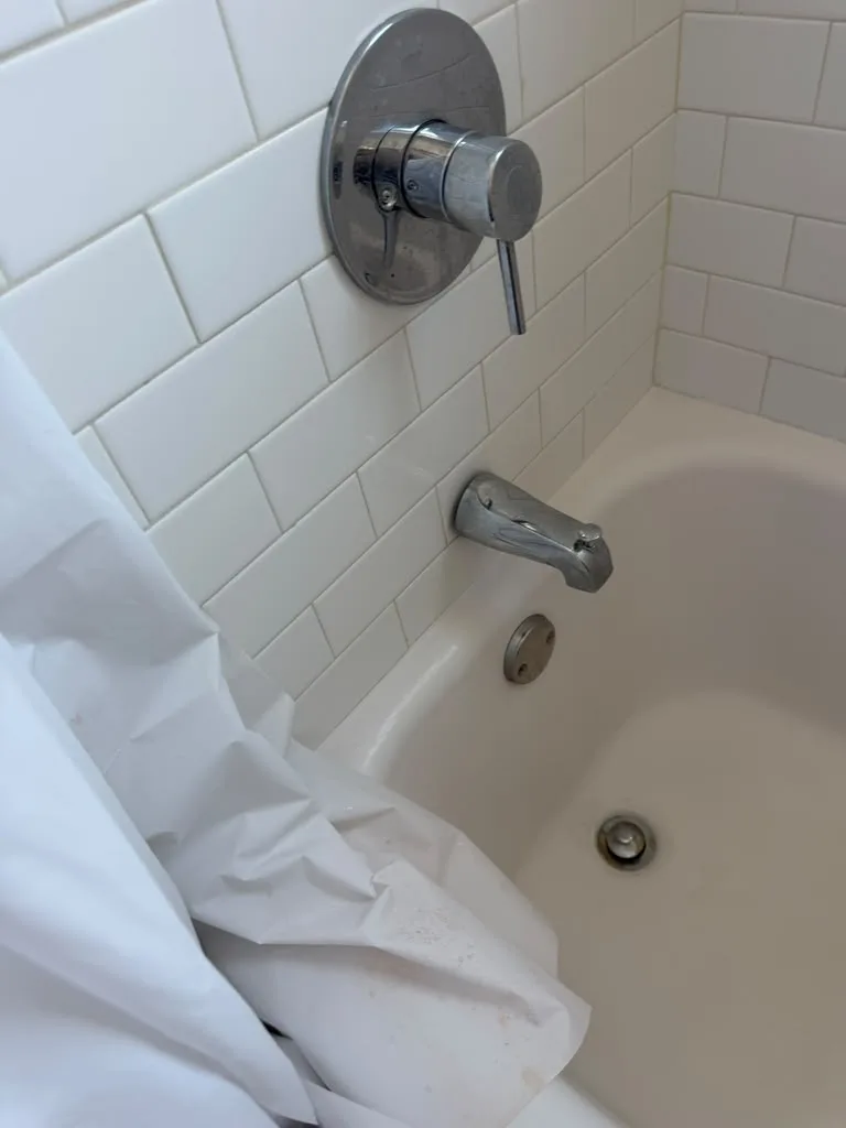 Tub spout and shower valve installed on a white subway tile wall