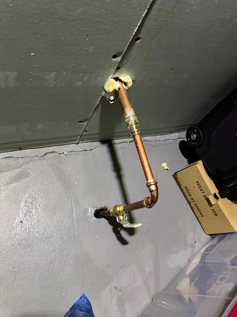 New copper pipe and shutoff valve installed along a garage wall